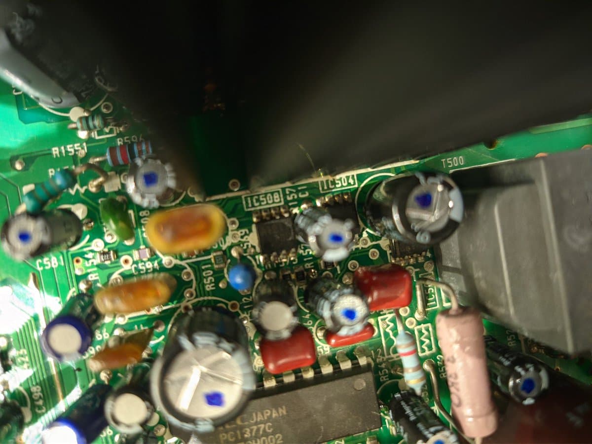 Close-up of Sony PVM-14M4J A board showing reflowed solder joints, replaced capacitors marked with dots, and various components including inductors and IC chips.