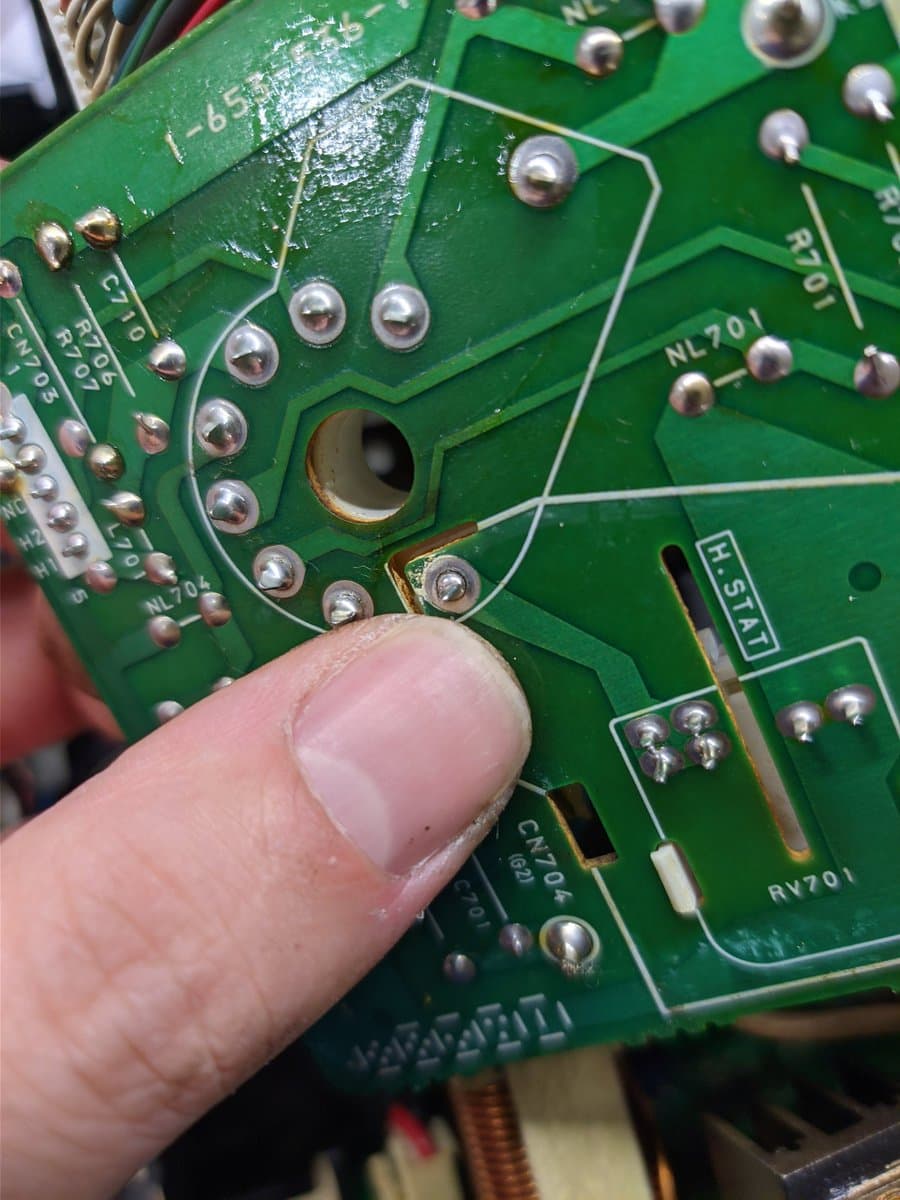 Finger pointing to reflowed solder joint on Sony BVM neckboard, showing repaired connection that caused color loss.