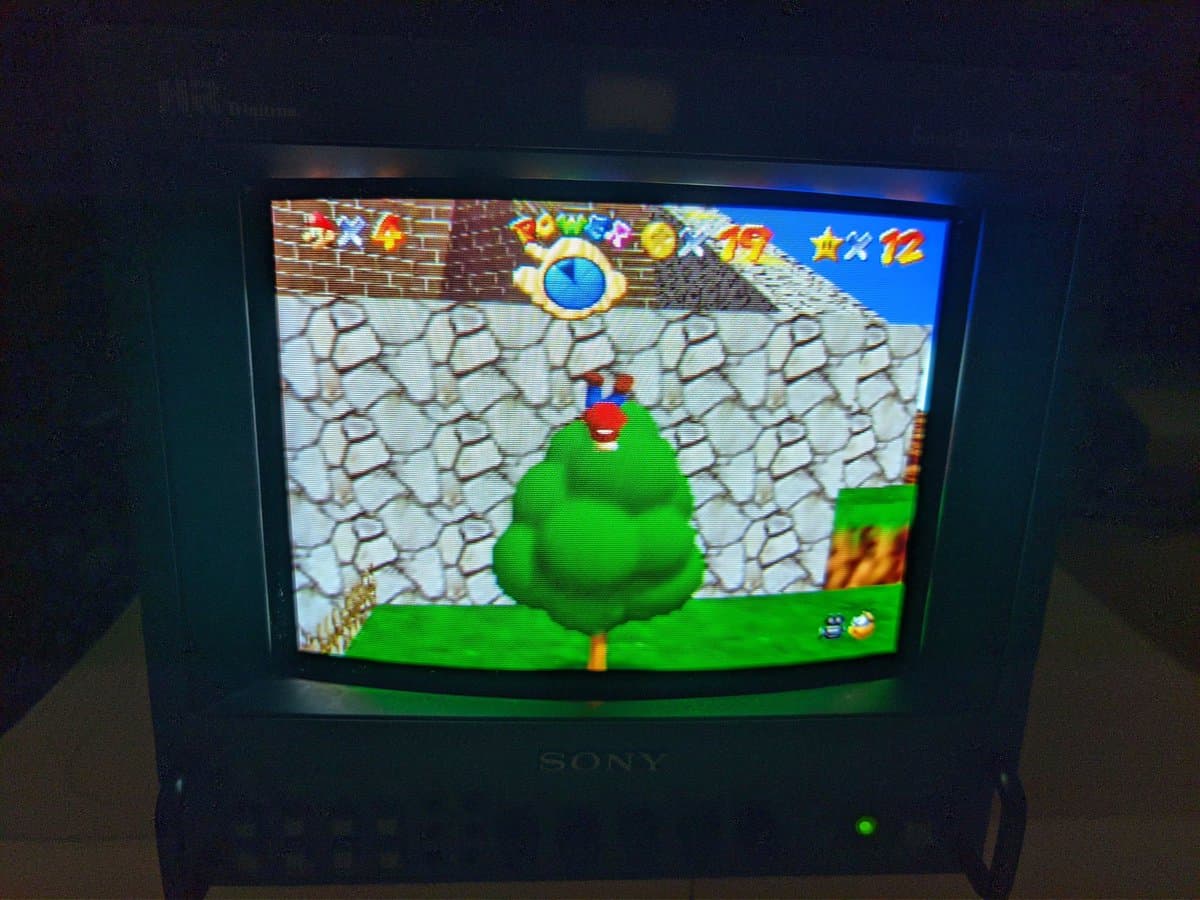 Sony BVM-9045QD CRT displaying Super Mario 64 on N64 after restoration; green castle environment visible with HUD elements.