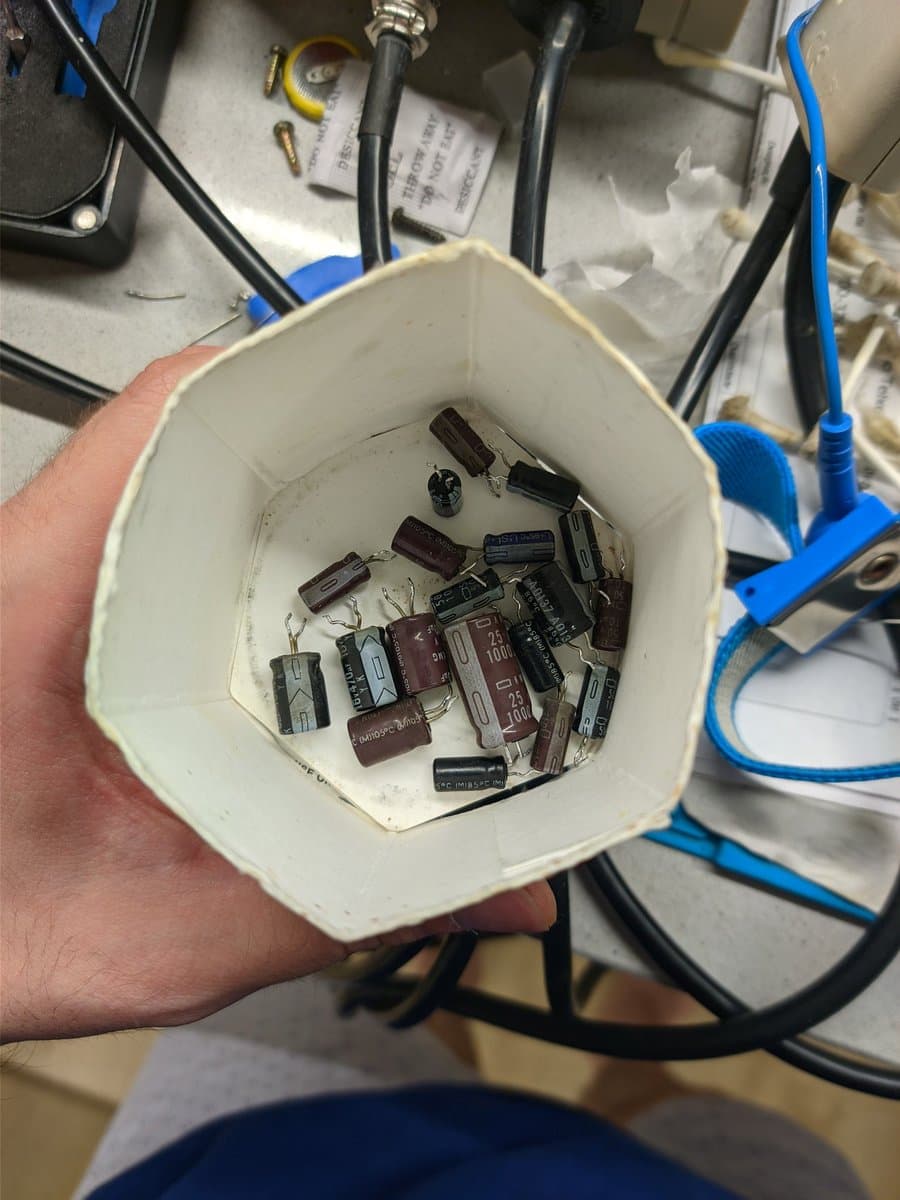 White container holding recapped electrolytic capacitors from Sony BVM-9045QD deflection board restoration, showing old and new components.