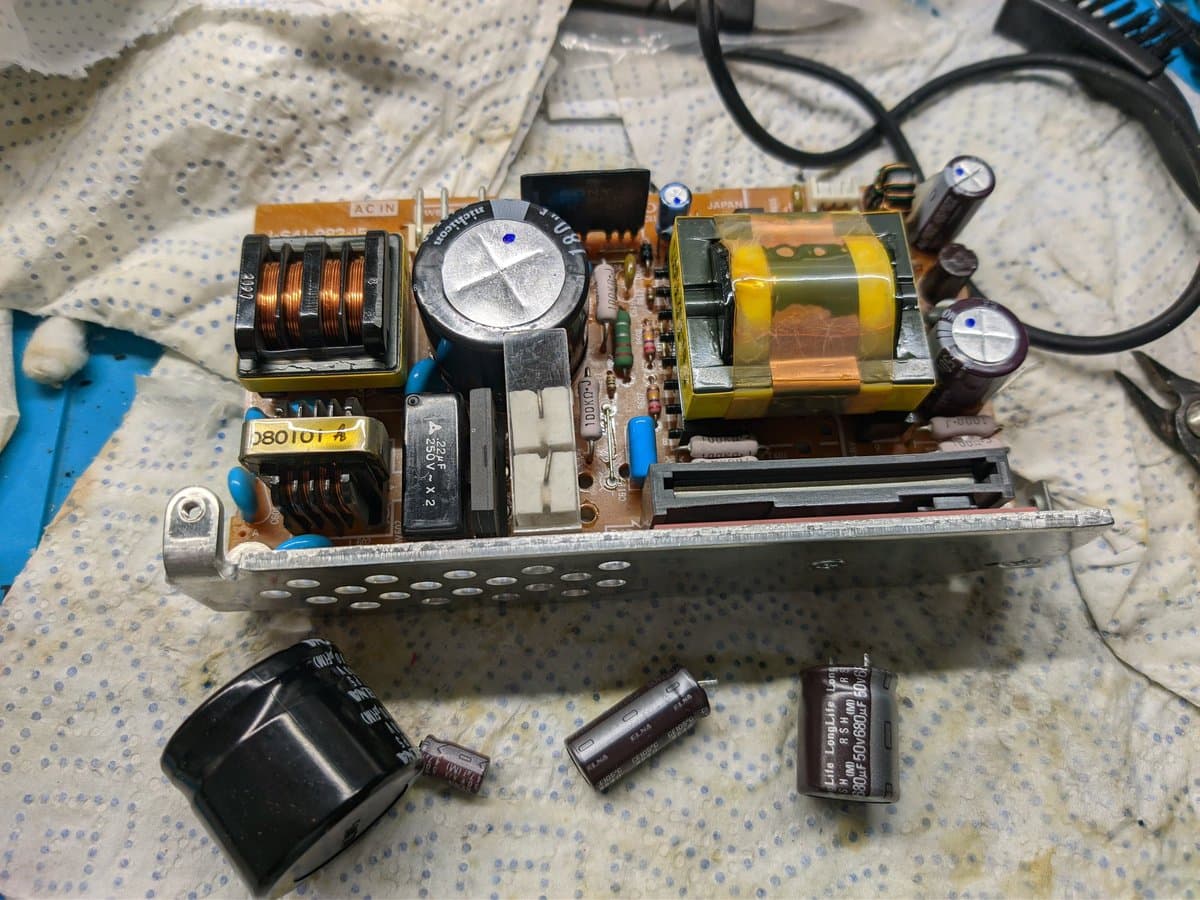 Disassembled PVM-9040 power supply unit showing transformer, capacitors, inductors, and circuitry laid out for inspection during restoration work.