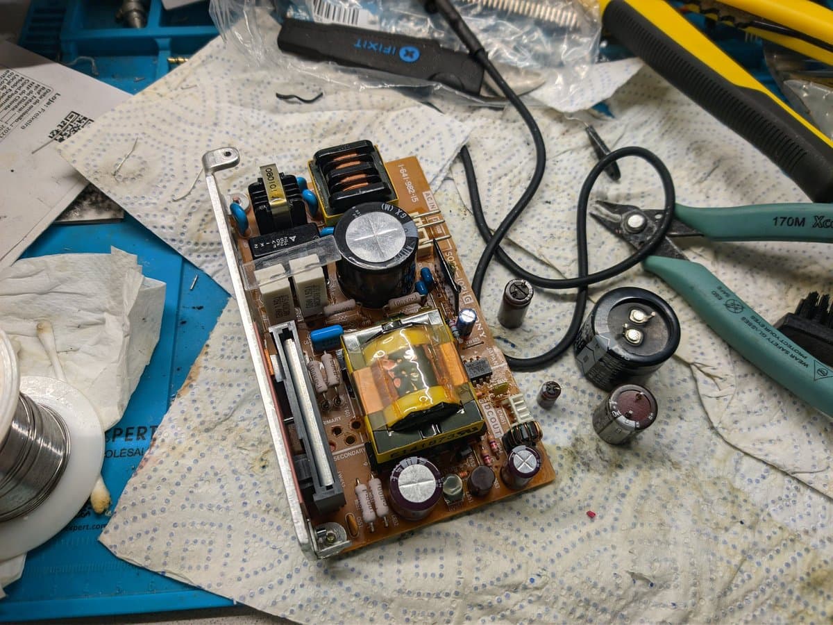 Disassembled Sony PVM-9040 PSU board showing capacitors, transformers, and inductors during inspection; no visibly bulging capacitors present.