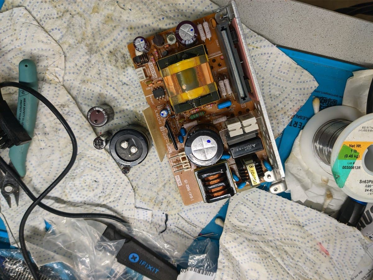 Disassembled PVM-9040 PSU board with capacitors, transformers, and inductors laid out for inspection during restoration work.