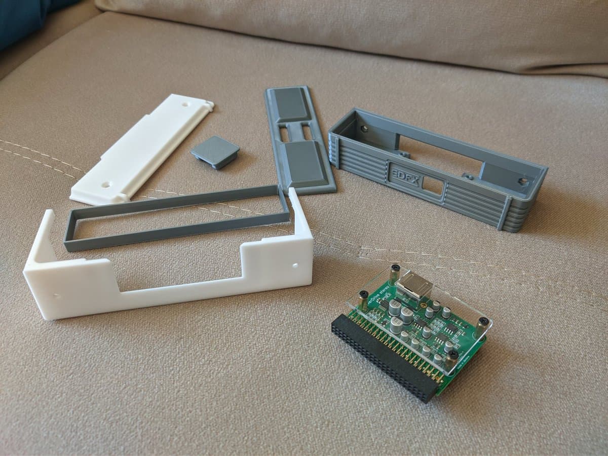 Disassembled SuperGrafx components laid out: white plastic shell parts, gray metal shielding, EDFX cartridge module, and green circuit board with capacitors during refurbishment.
