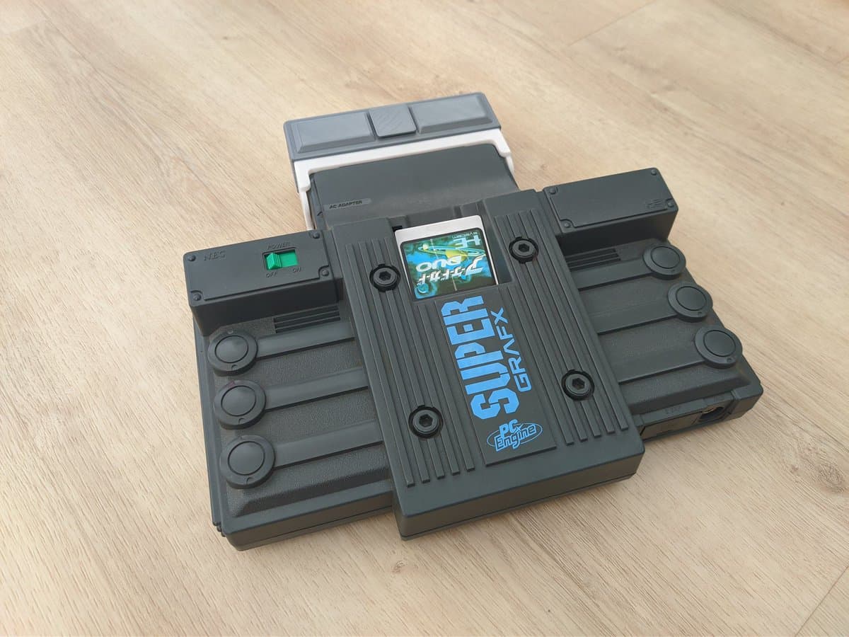 Refurbished NEC PC Engine SuperGrafx with EDFX flash cartridge in 3D-printed mini-IFU shell, displayed on wooden surface.