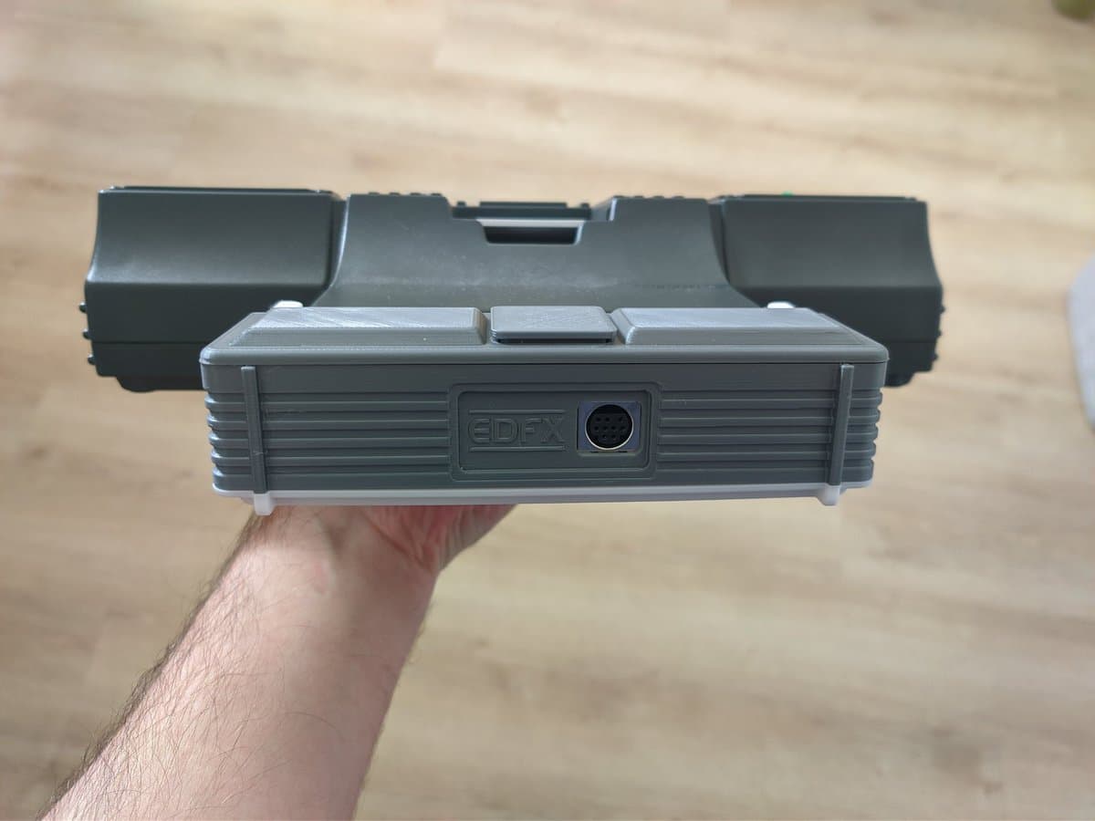 EDFX cartridge in 3D-printed mini-IFU shell, front view showing EDFX branding and lens port, held in hand above wooden surface.