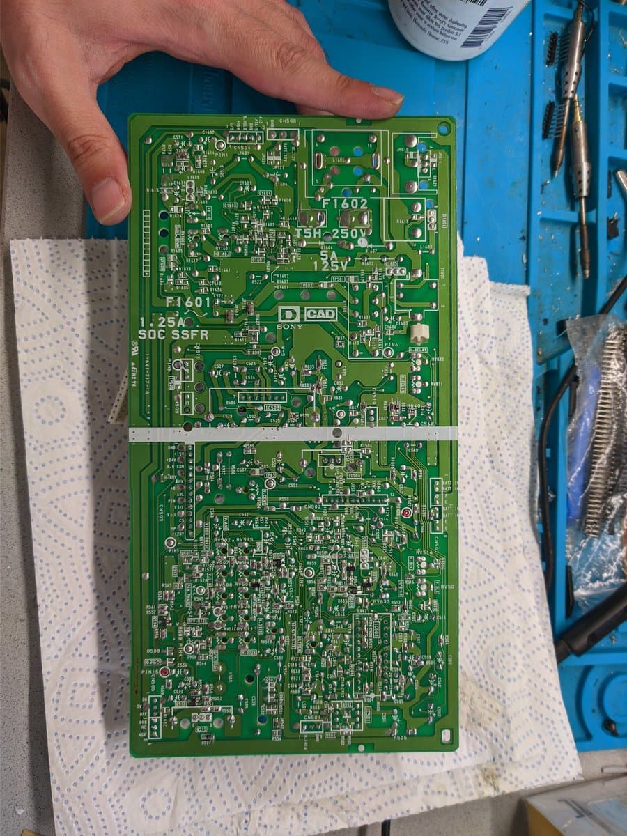 Sony PVM-9040 circuit board held in hand over white ESD mat, showing component layout and solder joints during repair diagnostics.