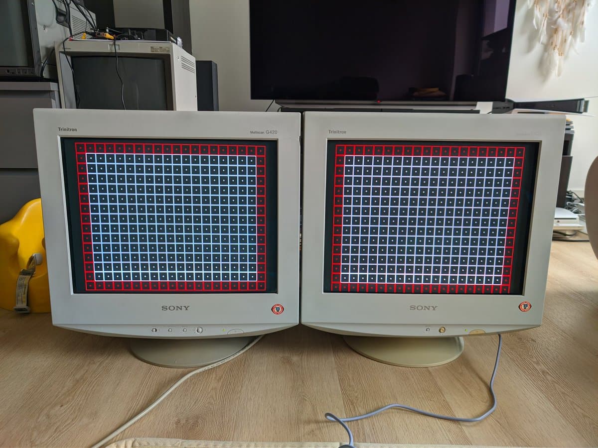 Two Sony Trinitron CRT monitors displaying red and blue test patterns side-by-side, comparing G420 and E430 calibration results post-repair.