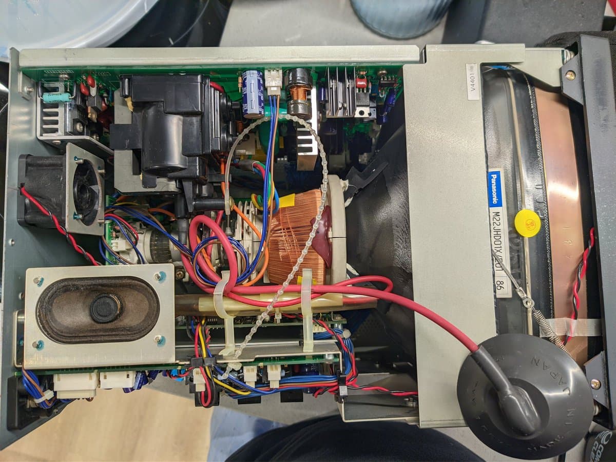 Interior of Ikegami TM10-17RA monitor showing power supply circuitry, transformer, capacitors, wiring harness, and speaker during voltage reconfiguration work.