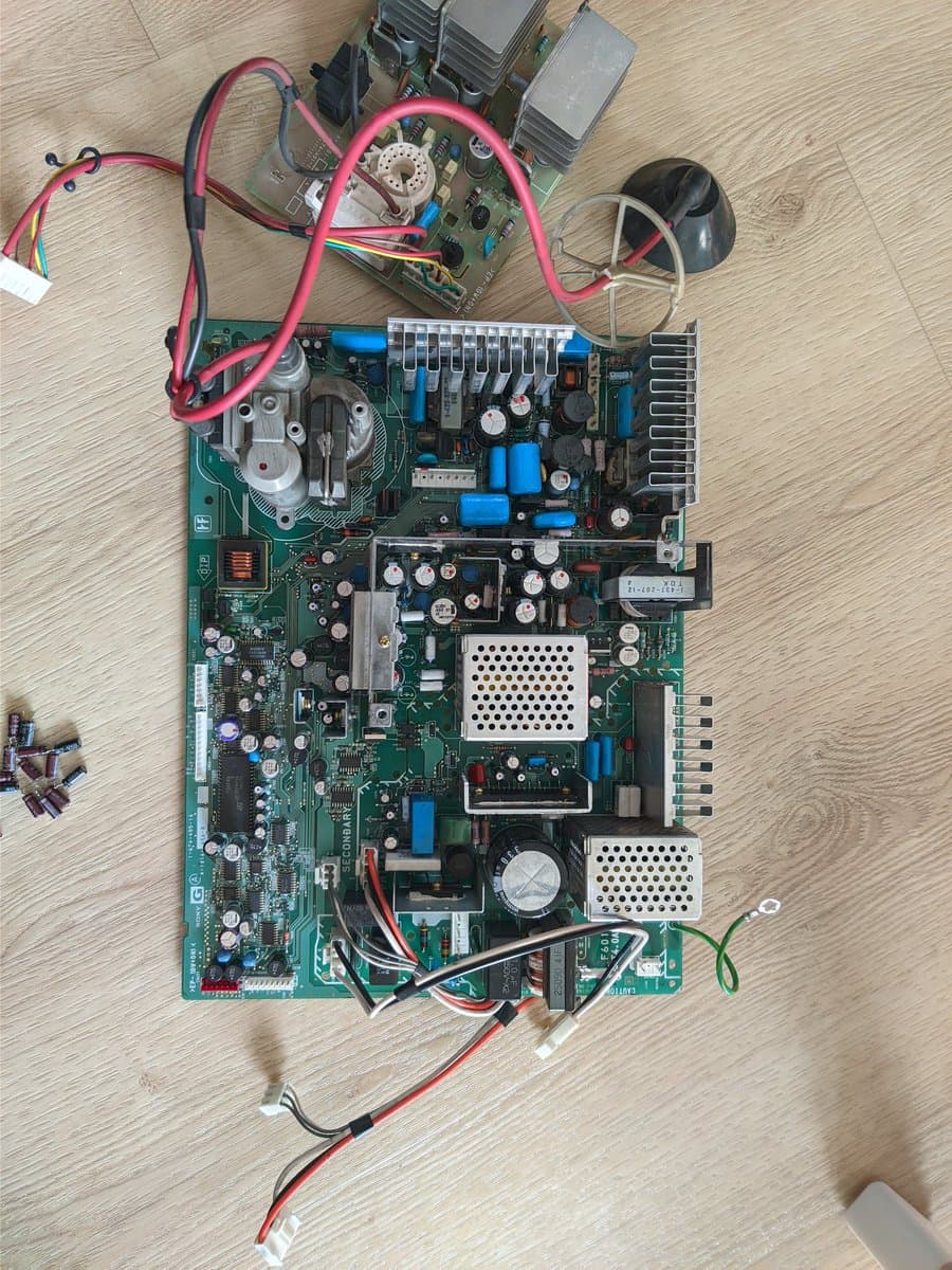 BVM-D14H1E main circuit board with fresh capacitor kit installed, showing blue capacitors and cleaned PCB with red power cables connected.