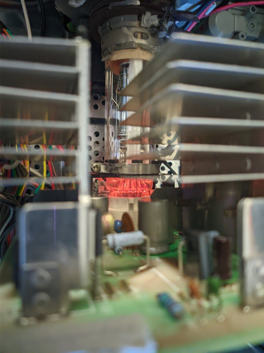 Close-up of Sony BVM-D14H1E internals showing glowing red component during restoration work, with ribbon cables and circuitry visible.