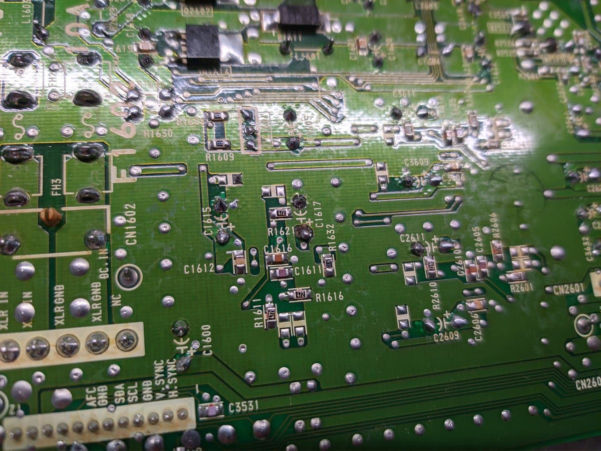 Close-up of Sony BVM power supply board showing reflowed solder joints, capacitors C1611-C1612, resistors R1609-R1621, and sticky flux residue from previous rework.