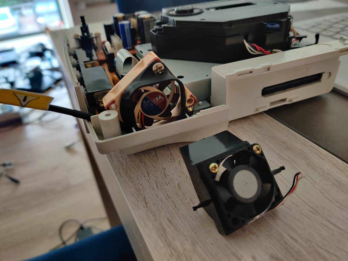 Noctua replacement fan installed in Dreamcast VA1 alongside original black fan, showing copper heatsink and internal cooling modification.