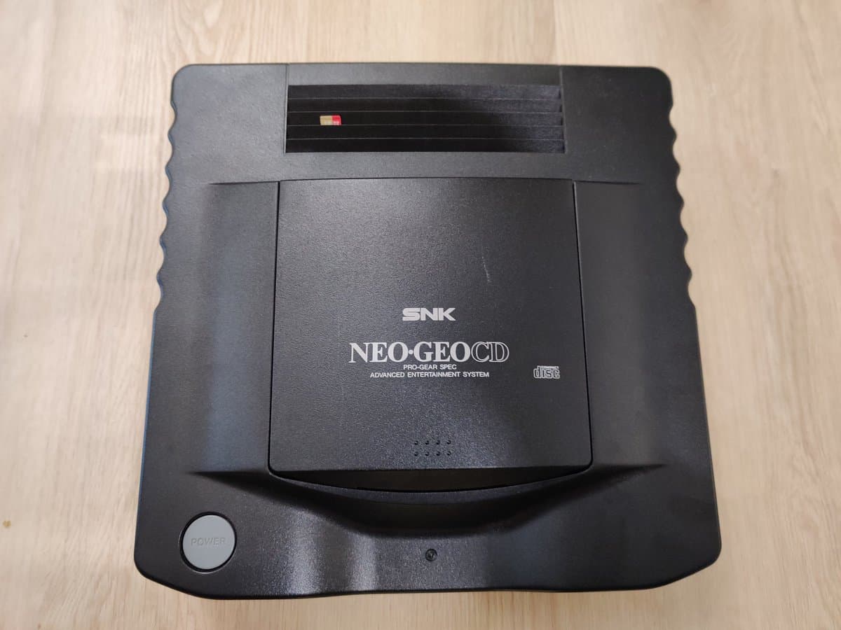 SNK Neo Geo CD console top view showing disc drive bay and power button, ready for SD loader and F-RAM upgrade installation.