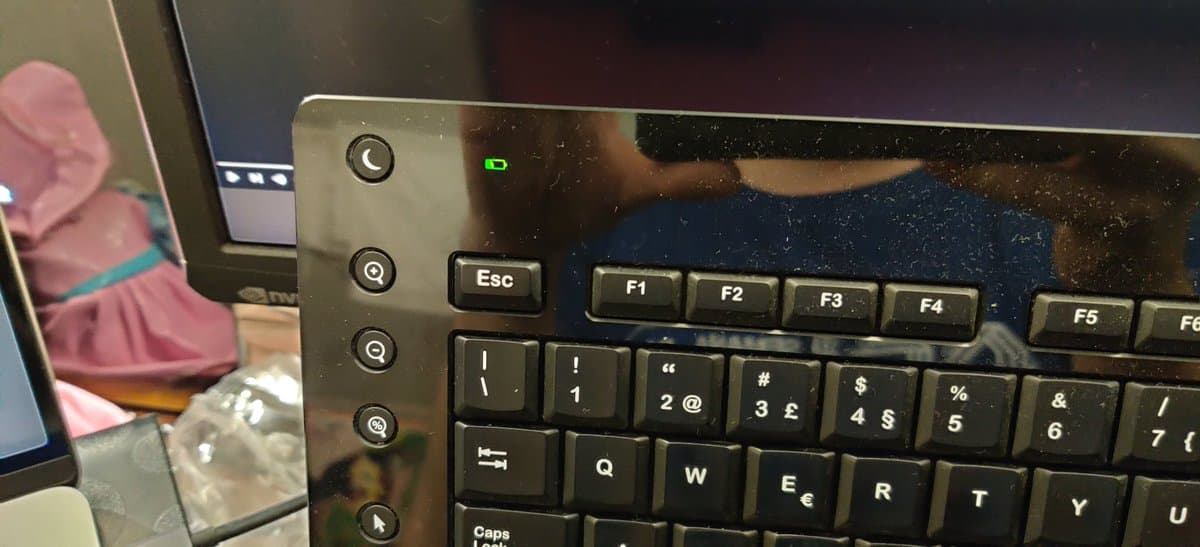 Logitech DiNovo Edge keyboard with charging dock connector visible, green LED indicator lit, showing restored barrel jack repair.