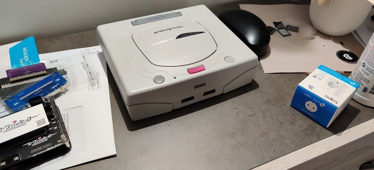 White GameCube with retrobrighting restoration next to black mouse on desk with spare parts and documentation visible.