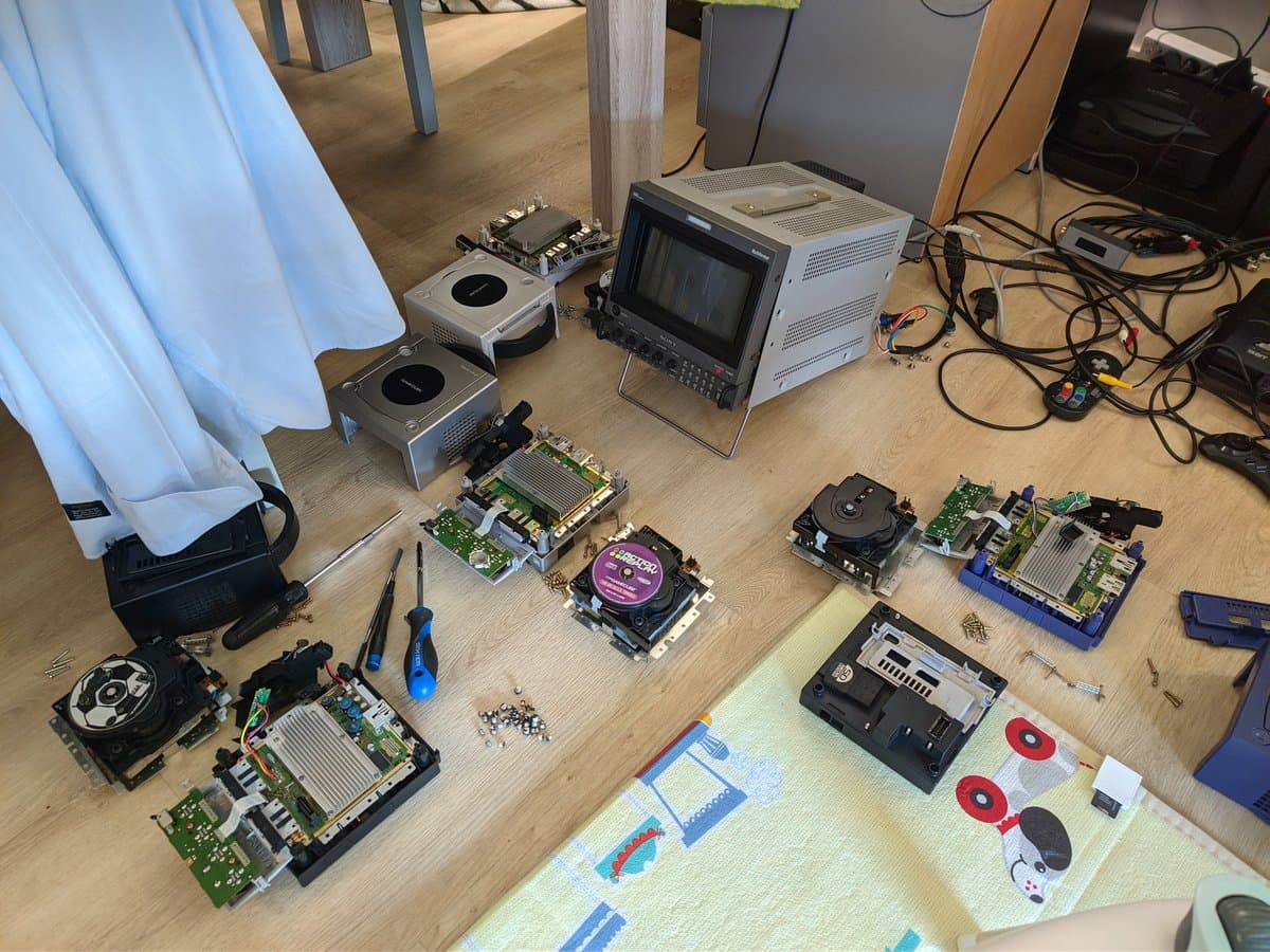 Disassembled GameCube optical drive PCBs laid out on workbench with capacitors, heatsinks, and soldering tools visible during restoration.