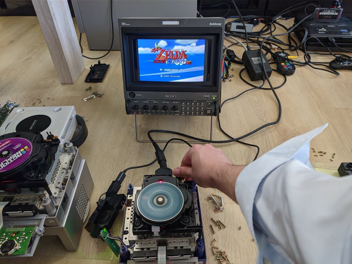 GameCube optical drive with replaced capacitors on workbench during restoration, disc tray open showing internal components.