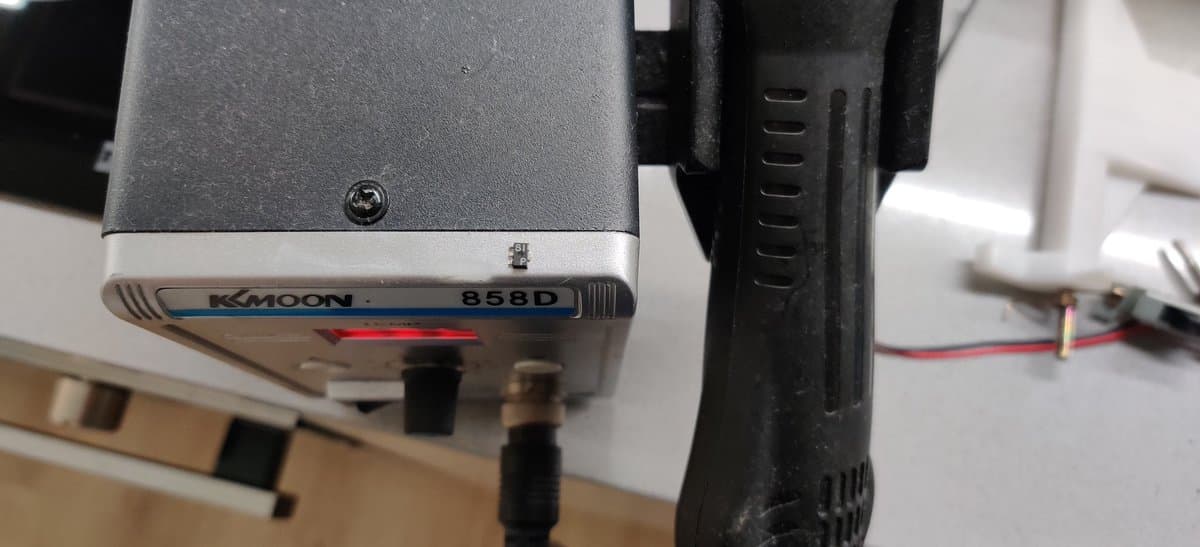 Moon 858D soldering iron with red LED indicator positioned over Super Famicom circuit board during D1 diode replacement repair.