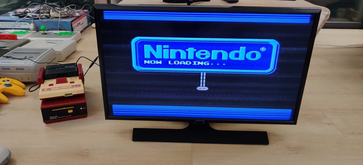 Famicom Disk System displaying "Now Loading" screen on monitor during belt replacement and alignment refurbishment repair.