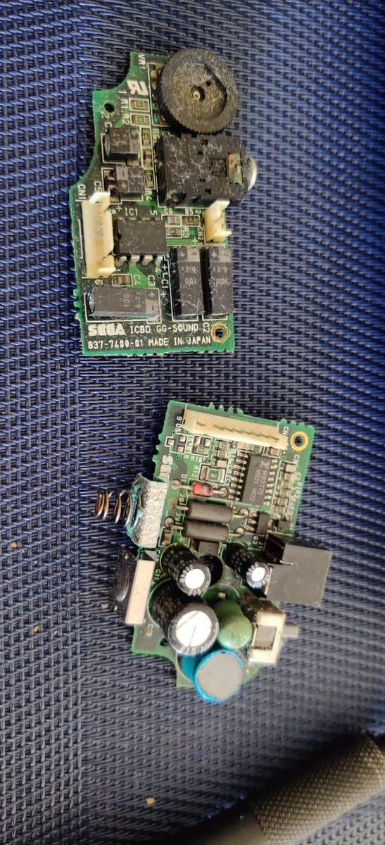 Two Sega Game Gear circuit boards showing capacitor replacement and solder joint reflowing work during restoration repair.