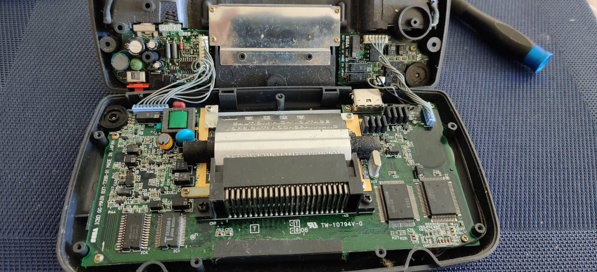 Disassembled Sega Game Gear motherboard showing reflowed solder joints and replaced capacitors during restoration work.