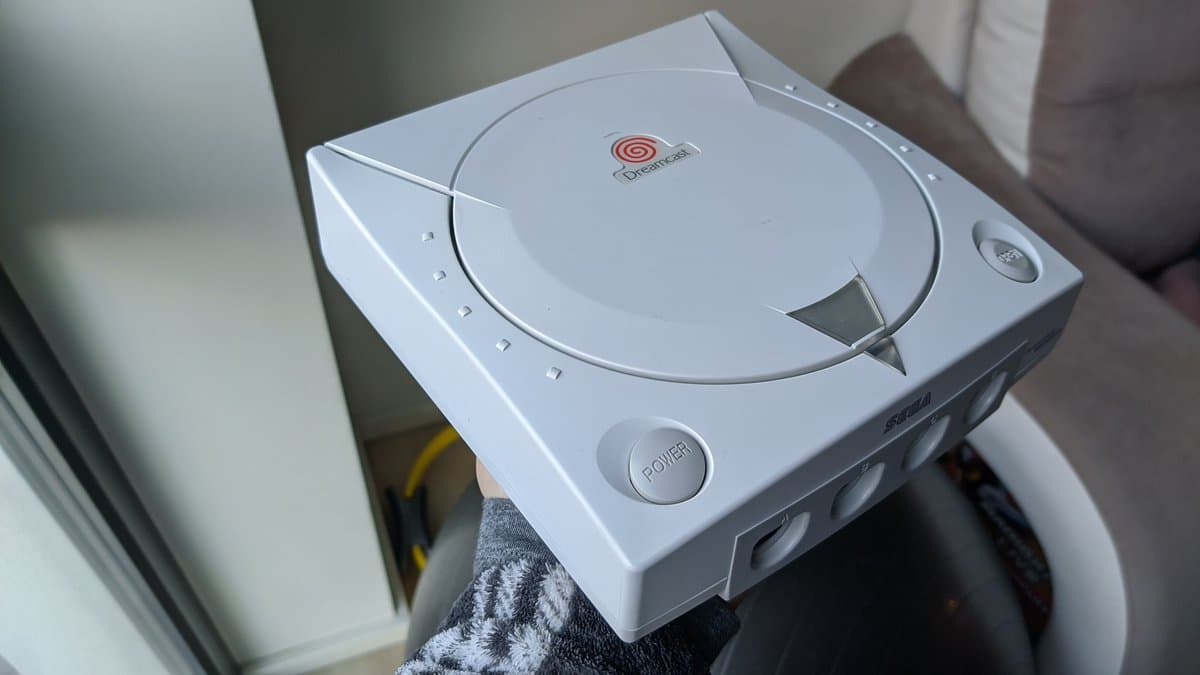 White Sega Dreamcast VA0 console with disc tray open, showing Dreamcast branding and power button, positioned on towel during refurbishment.