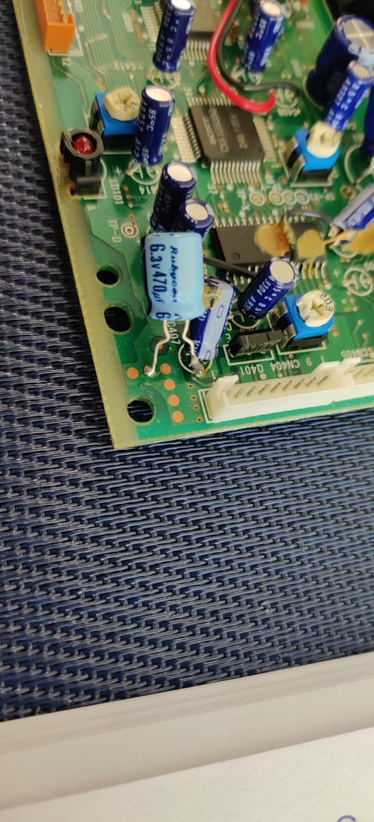 Sega Mega-CD 2 motherboard showing factory bodge wiring with blue capacitors, IC chips, and hand-written label identifying original factory modifications.