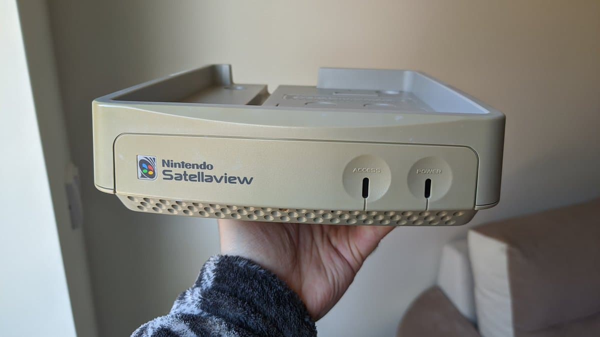 Nintendo SatellaView shell held in hand after retrobrighting, showing cream-colored plastic with ACCESS and POWER buttons visible.