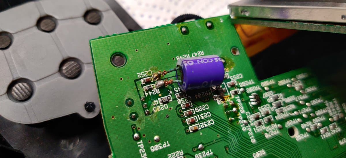 Close-up of Sega Nomad PCB showing removed capacitor and damaged solder joints from poor aftermarket screen installation work.