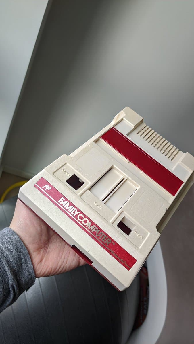 Repaired Famicom with composite mod board installed, showing white and red casing with new "FAMICOM" decal applied to front panel.