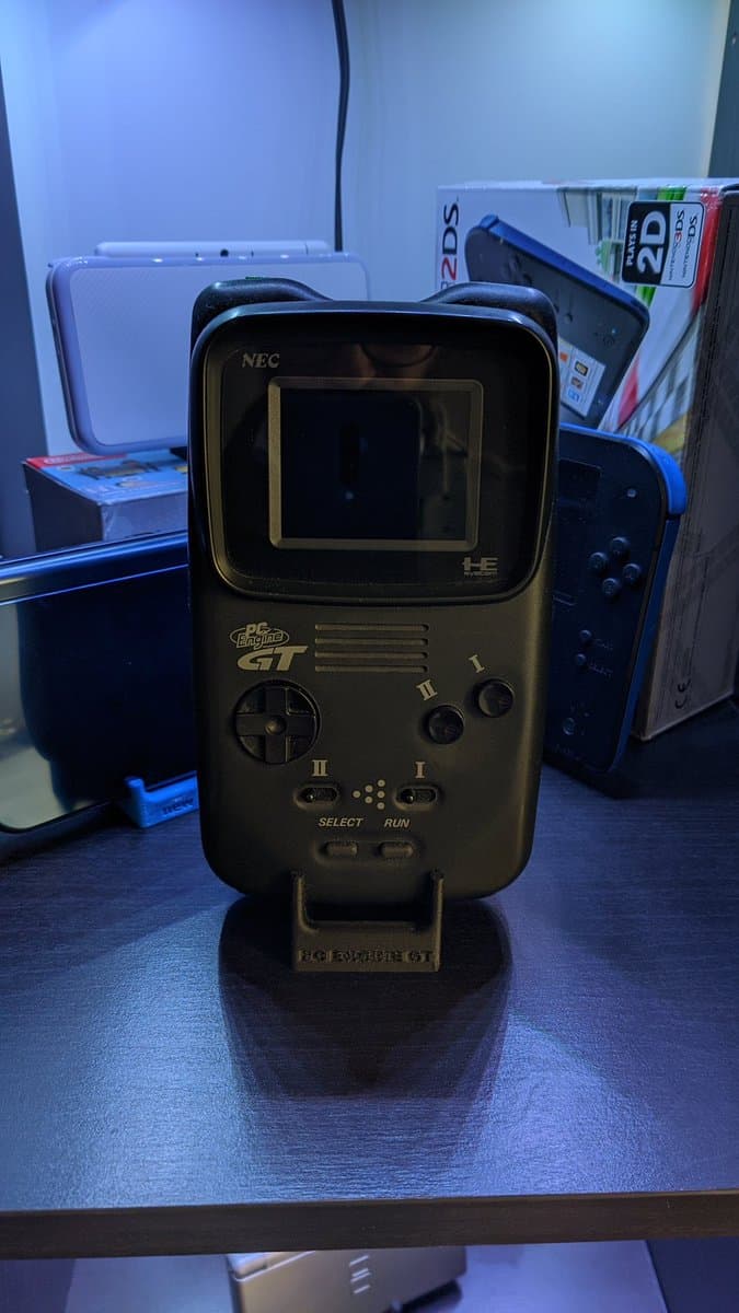 NEC PC Engine GT handheld console on display stand, showing front panel with screen, d-pad, and buttons after capacitor replacement refurbishment.