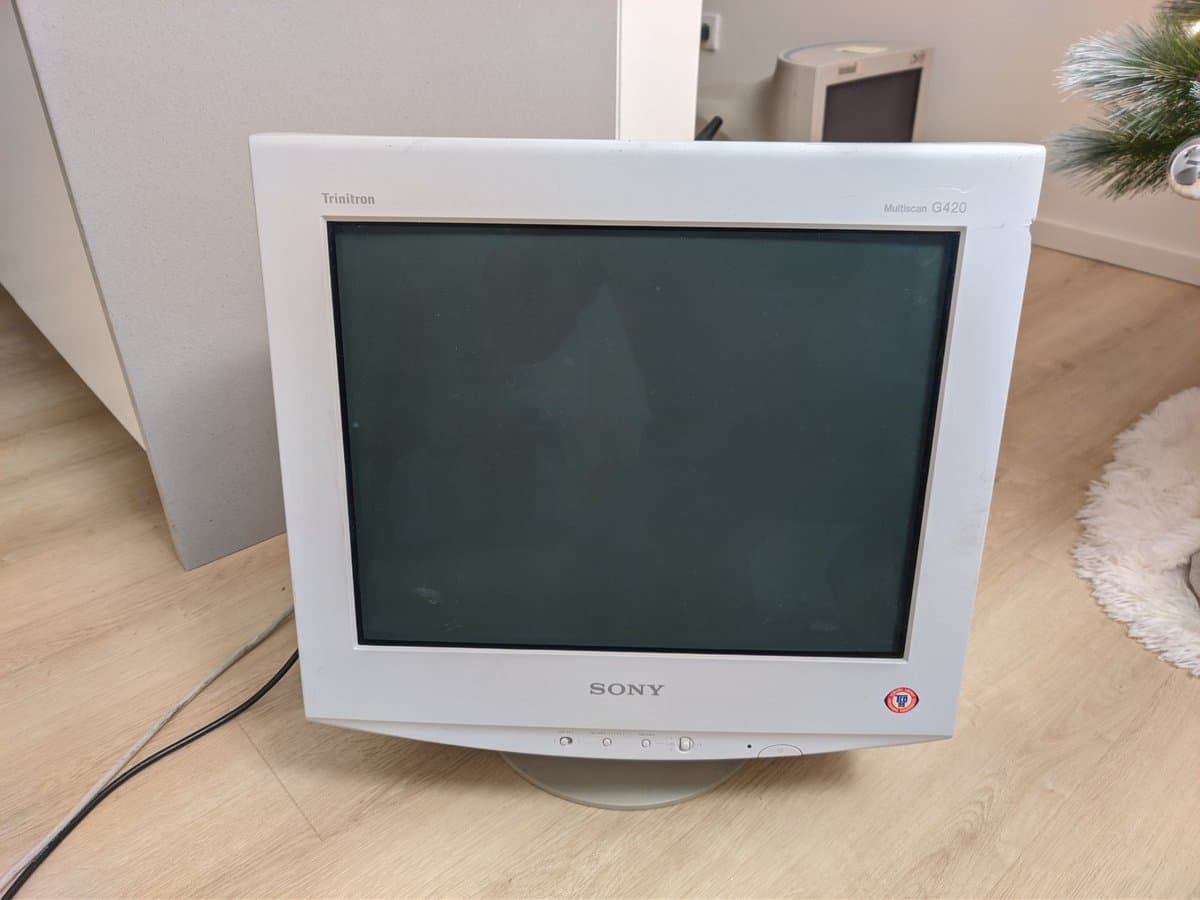 Sony CPD-G420 CRT monitor displaying dark screen on wooden floor during diagnostic evaluation for geometry and clicking issues.