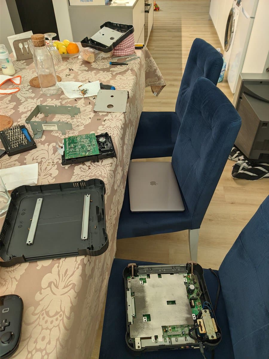 Panasonic FZ-1 motherboard and PSU components laid out on table during restoration, with laptop and tools visible for testing repaired console.