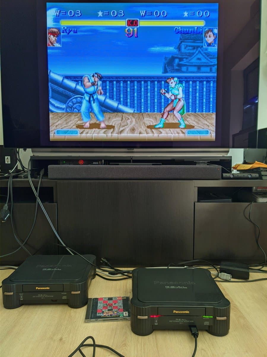 Two Panasonic 3DO consoles connected via daisy-chained controllers displaying Street Fighter II on TV; S-video output active.