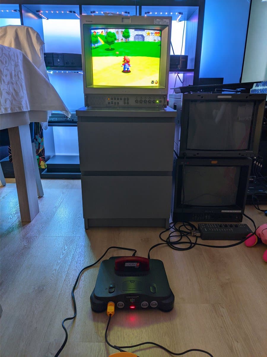 Nintendo 64 connected to CRT monitor displaying Super Mario 64 gameplay, controller in foreground, testing restored console after recap and service work.
