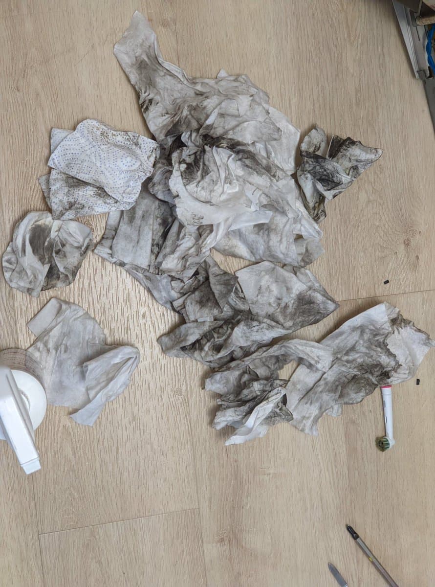 Heavily nicotine-stained fabric strips and components from Philips 109S4 CRT disassembly, with cleaning tools and brushes on wooden surface.