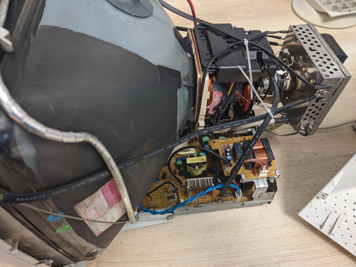 Disassembled Philips 109S4 CRT monitor showing yellowed power supply PCB with Capxon capacitors, deflection circuitry, and internal components during restoration work.