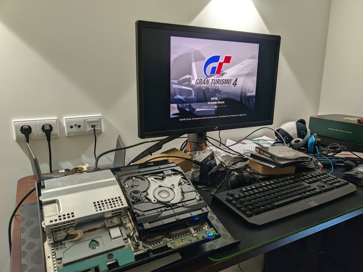 Disassembled PS3 CECHB00 showing disc drive mechanism with tray assembly, laser head, and internal components during cleaning and lubrication repair.