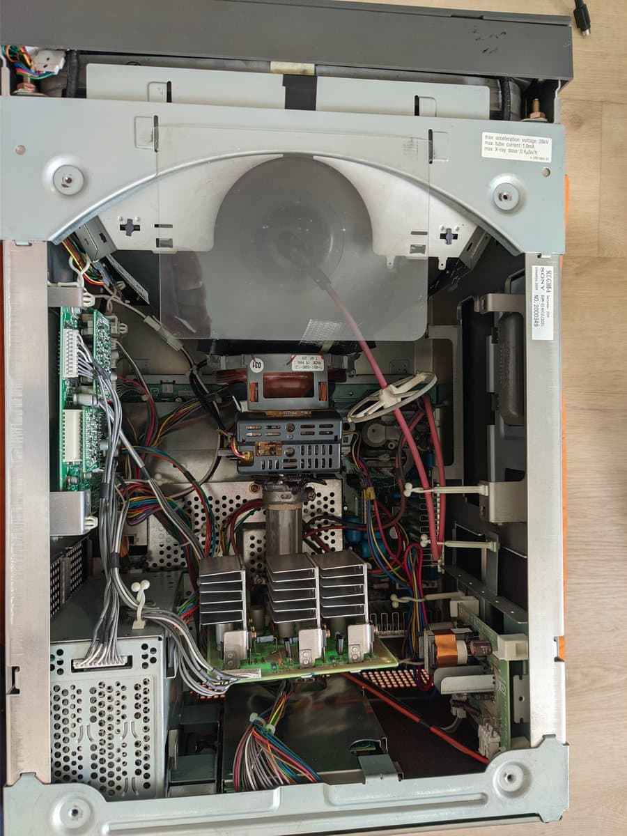 Sony BVM-D14H1E interior showing circuit boards, power supply heatsinks, deflection coils, and wiring during restoration work.