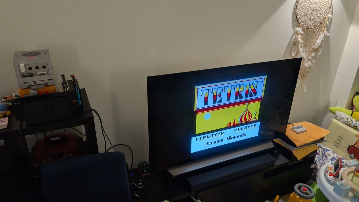 Tetris title screen displayed on TV connected to recapped Game Boy Player, with GameCube console and repair tools visible on desk.
