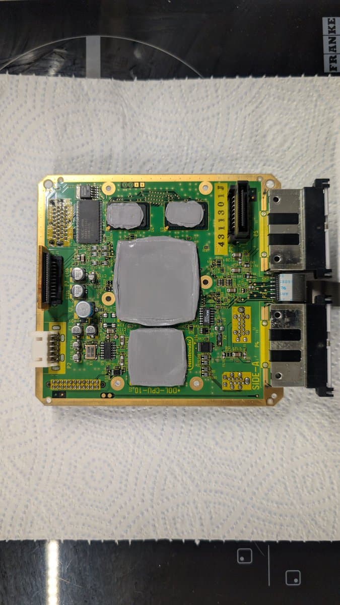 Panasonic Q motherboard with recapped capacitors, two large heatsinks, and black connectors visible during FlippyDrive reinstallation.