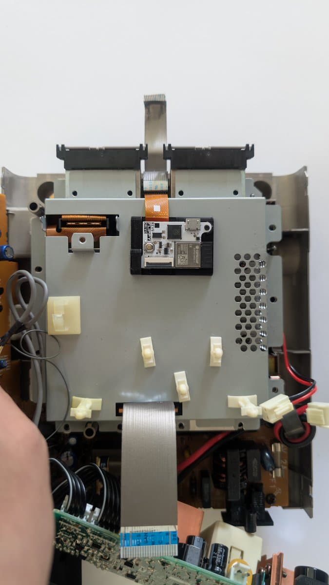 Panasonic Q motherboard showing FlippyDrive installation with flex cable routed beneath shielding, optical drive components visible above.