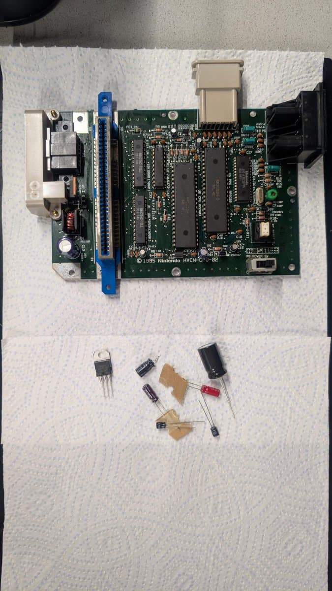 AV Famicom motherboard with removed capacitors displayed below; full recap in progress after cleaning oxidized cartridge slot.