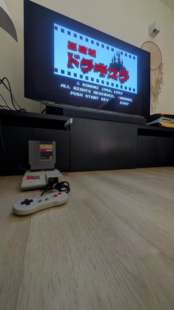 Nintendo AV Famicom displaying Castlevania title screen with original controller and game cartridge on wooden surface after recap repair.
