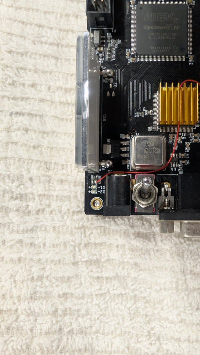 OSSC classic circuit board showing Cyclone IV FPGA chip, CPU, memory modules, and power components during firmware modding procedure.