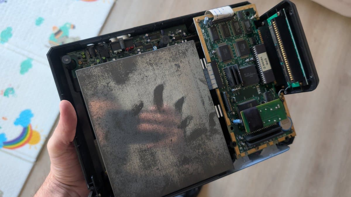 Sega Mega-CD 1 opened showing heavily corroded circuit boards with leaked capacitors; internal PCBs visible on right side.