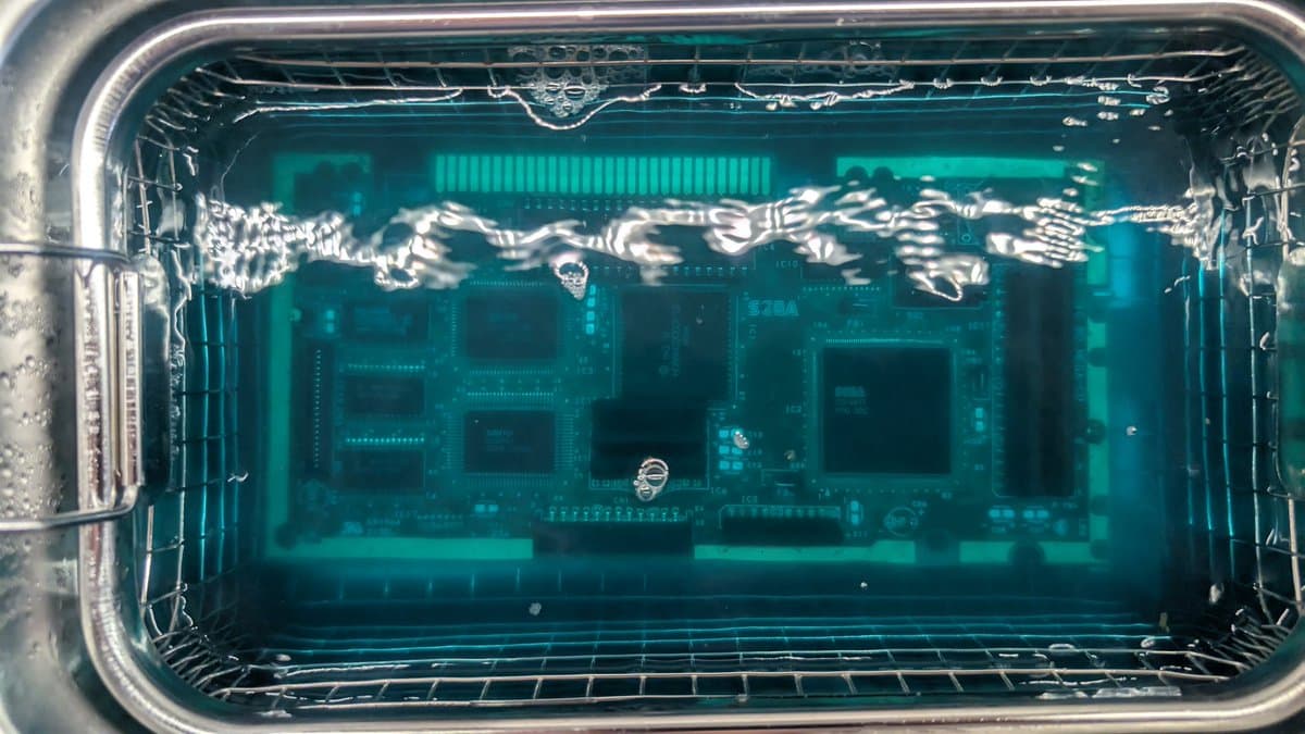 Sega Mega-CD 1 motherboard in metal tray showing extensive capacitor leakage damage and corrosion across PCB during recapping restoration.