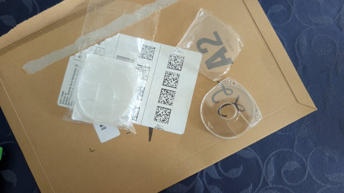 Unboxed PSP replacement parts: screen protectors in plastic packaging, QR code documentation sheet, and two clear plastic cases with circular logos.