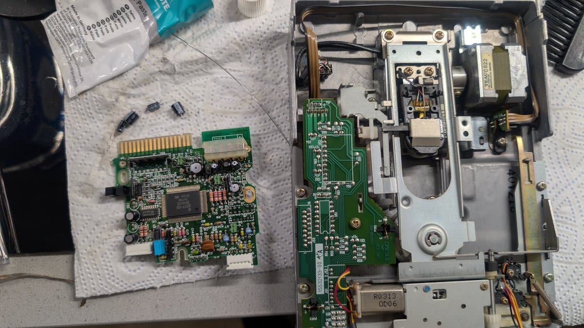 Disassembled X68000 Pro II motherboard and drive control board during recap, showing replaced capacitors and cleaned PCB components on work surface.